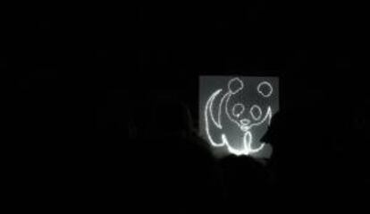 Silueta de un oso panda, logotipo de la organización ecologista World Wildlife Fund (WWF), en un panel encendido con energía limpia generada por bicicletas durante el apagado de luces llevado a cabo durante una hora, en la Plaza de Oriente de Madrid, el año pasado. EFE/Archivo
