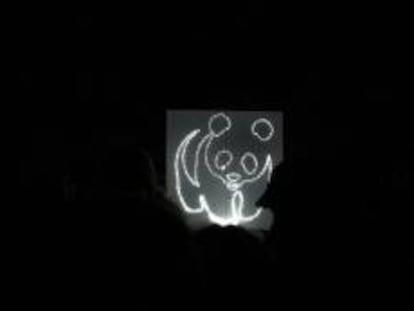 Silueta de un oso panda, logotipo de la organización ecologista World Wildlife Fund (WWF), en un panel encendido con energía limpia generada por bicicletas durante el apagado de luces llevado a cabo durante una hora, en la Plaza de Oriente de Madrid, el año pasado. EFE/Archivo