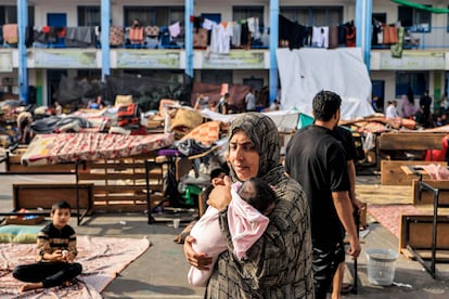 Una mujer camina junto a su bebé en el interior del patio de una escuela de la Agencia de la ONU para los Refugiados Palestinos convertido en un campamento para los desplazados por la guerra, este miércoles en Jan Yunis. 