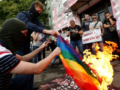 FILE - Anti-LGBT protesters burn an LGBT flag at the International Amnesty building during the opening ceremony of the Pride Week in Kyiv, Ukraine, Tuesday, June 13, 2017. Despite the war in Ukraine, the country's largest LGBT rights event, KyivPride, is going ahead on Saturday, June 25, 2022. But not on its native streets and not as a celebration of gay pride. It will instead join Warsaw's yearly Equality Parade, using it as a platform to keep international attention focused on the Ukrainian struggle for freedom. (AP Photo/Sergei Chuzavkov, File)