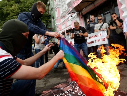 FILE - Anti-LGBT protesters burn an LGBT flag at the International Amnesty building during the opening ceremony of the Pride Week in Kyiv, Ukraine, Tuesday, June 13, 2017. Despite the war in Ukraine, the country's largest LGBT rights event, KyivPride, is going ahead on Saturday, June 25, 2022. But not on its native streets and not as a celebration of gay pride. It will instead join Warsaw's yearly Equality Parade, using it as a platform to keep international attention focused on the Ukrainian struggle for freedom. (AP Photo/Sergei Chuzavkov, File)