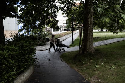 Una mujer empuja a una anciana en silla de ruedas en un parque en Grado, Asturias.