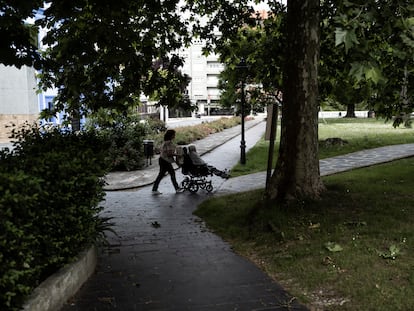 Una mujer empuja a una anciana en silla de ruedas en un parque en Grado, Asturias.