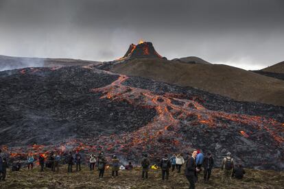 La gente observa y toma fotos mientras la lava fluye desde un volcán en la península de Reykjanes, en el suroeste de Islandia. La erupción está atrayendo a multitudes que esperan acercarse a los suaves flujos de lava. Este fenómeno de la naturaleza, cerca de la capital de Islandia, Reikiavik, no se ve como una amenaza para las ciudades cercanas y los flujos lentos significan que la gente puede acercarse sin un alto grado de riesgo.