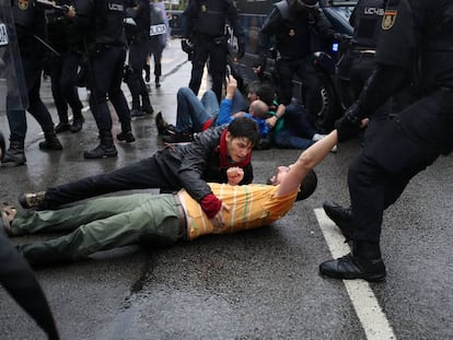 Riot police remove demonstrators outside a polling station for the banned independence referendum in Barcelona.