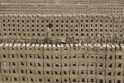 Un niño transporta arcilla para hacer ladrillos a mano en Calcuta (India). El trabajo infantil nutre a grandes empresas.