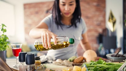 Una mujer echando en la comida aceite de oliva