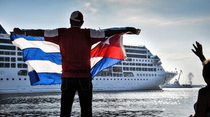 Un hombre ondea una bandera de Cuba desde el Malecón de La Habana a la llegada del Adonia.