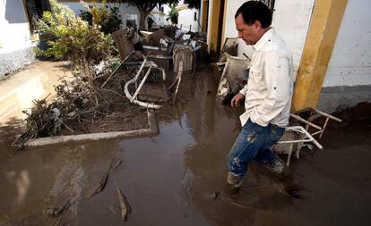 Un vecino anda por las calles llenas de fango arrasadas por la riada en Pueblo Laguna, Almería.
