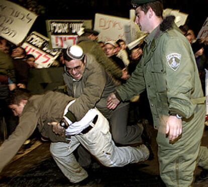 Un polícía detiene ayer a un manifestante derechista frente al lugar en el que Sharon celebraba una reunión de seguridad.