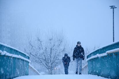 Unos estudiantes cruzan un puente nevado en Lleida