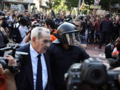 Ernest Maragall, del PSC, escoltado por los mossos durante la concentración de indignados las puertas del Parlament de Cataluña.