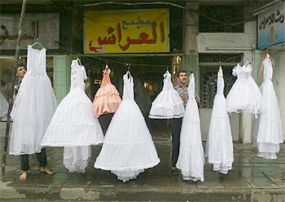 Dos comerciantes cuelgan vestidos de novia frente a su establecimiento, ayer en Bagdad.