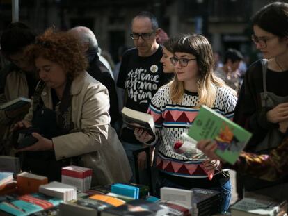 Una joven sostiene un libro y una rosa en una de las paradas de La Rambla, en la festividad de Sant Jordi de 2019.