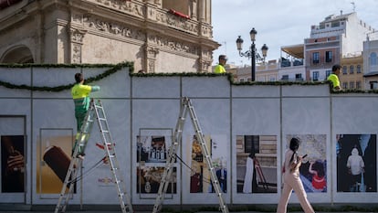 Tres operarios preparan los palcos de la Semana Santa, decorados con una exposición de fotografías, en la Plaza de San Francisco, Sevilla.