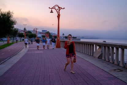 Una mujer lee mientras pasea, en La Coruña, este agosto.