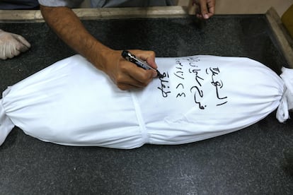 Un médico escribe el nombre Farah abu Shabab en el cuerpo envuelto de un niño muerto en un ataque israelí, en el hospital Najjar, en Rafah, en el sur de la franja de Gaza.