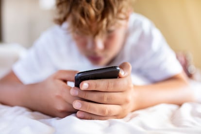 Un adolescente usa un teléfono móvil.