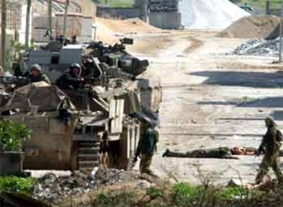 Un tanque isrealí, al lado de los cuerpos de dos policías palestinos, ayer, a la entrada de Beit Hanun (Gaza).