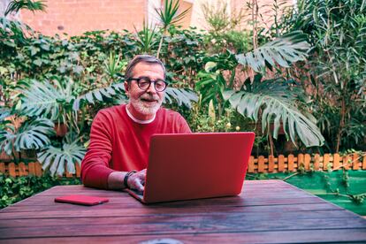 a senior man working in his garden with a laptop computer