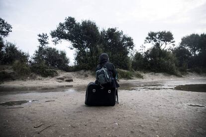 Un migrante espera junto a su equipaje en el campamento en Calais (Francia).