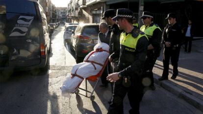 Agentes de la Policía Municipal y empleados de los servicios funerarios trasladan el cadáver de la mujer degollada en Puente de Vallecas.