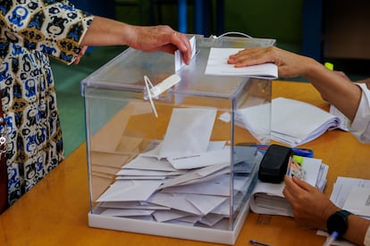 Una mujer introduce su voto en una urna en un colegio electoral de Sevilla.