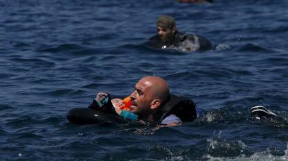 Un refugiat sirià amb un nadó en braços neda cap a la costa de Lesbos després de naufragar l'embarcació on anava.
