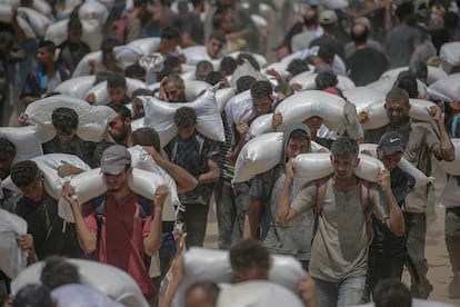 Palestinos desplazados cargan sacos de harina cerca de un punto de distribución de alimentos en Zikim, al norte de Gaza, el 27 de julio de 2025.