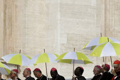 Un grupo de obispos sostiene paraguas con la bandera del Vaticano para protegerse del sol durante la audiencia semanal del papa Francisco, en la plaza de San Pedro (Ciudad del Vaticano).
