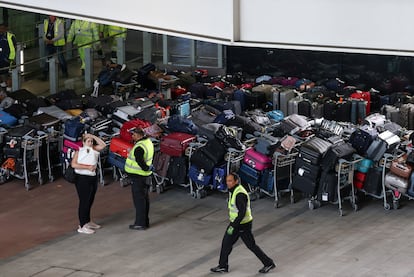 Trabajadores del aeropuerto de Heathrow en Londres junto a maletas apiladas en la terminal 2, el pasado 19 de junio.