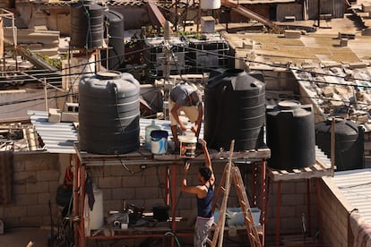 Dos hombres llenan depósitos de agua en la ciudad de Rafah.