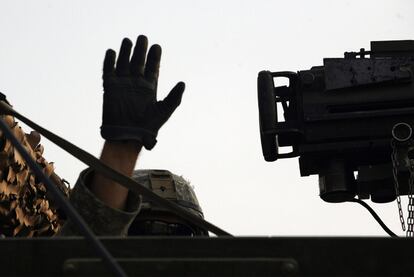 Un soldado estadounidense saluda con la mano tras cruzar con su vehículo la frontera iraquí.