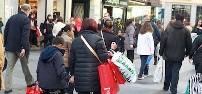 Un grupo de personas pasean con sus compras por la popular calle comercial madrile&ntilde;a de Preciados. 