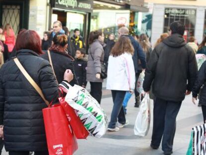 Un grupo de personas pasean con sus compras por la popular calle comercial madrile&ntilde;a de Preciados. 