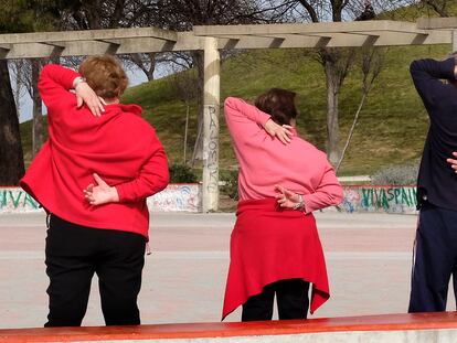 A group of elderly individuals exercises in a park in Madrid, Spain.