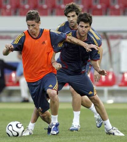 Torres protege el balón ante Cesc y Albelda, durante el entrenamiento previo al choque ante Túnez.