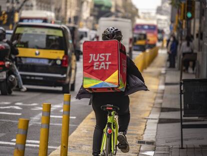 Un repartidor de Just Eat cruza en bicicleta la Via Laietana de Barcelona para entregar un pedido.