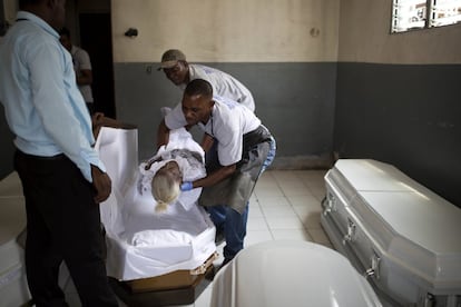 Arnold Destin (derecha), trabajador de una morgue, coloca el cuerpo de una mujer dentro de un ataúd, en la funeraria y morgue Zenith en Puerto Príncipe, Haití. Las funerarias establecidas quieren que las autoridades controlen a los funerarios independientes que les usurpan sus negocios.