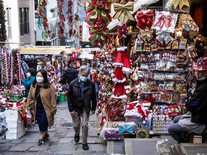 People (L) walk past a stall selling Christmas decorations in Hong Kong on December 2, 2022. (Photo by ISAAC LAWRENCE / AFP)