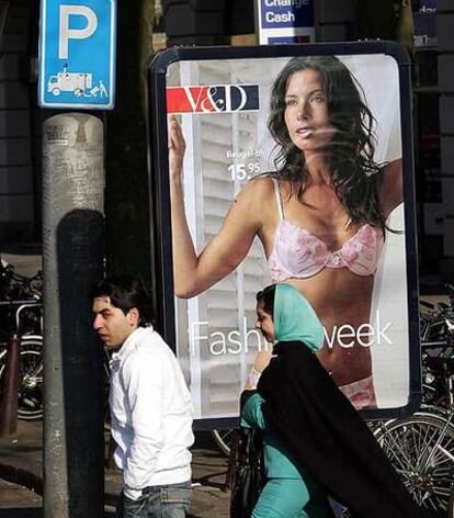 Una joven con velo islámico, frente a un anuncio de lencería, en Amsterdam.