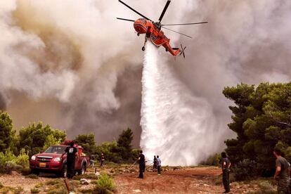 Un helicóptero de extinción de incendios lanza agua en la zona de Kineta.
