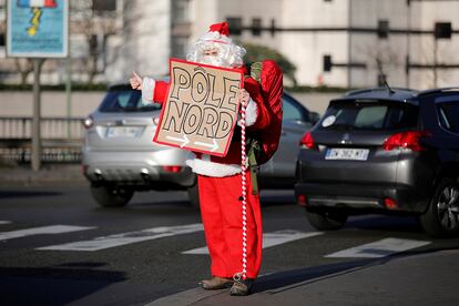 Un hombre vestido el traje de Santa Claus hace autostop en una calle de París (Francia), el 6 de diciembre de 2016.