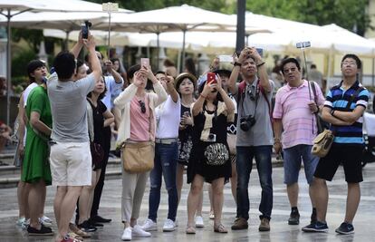 Un grupo de turistas fotografía un monumento en la plaza de la Virgen.