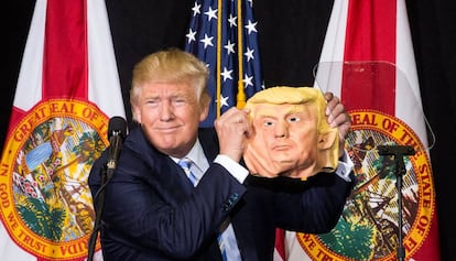 Donald Trump muestra una máscara de sí mismo en un mitin electoral . /