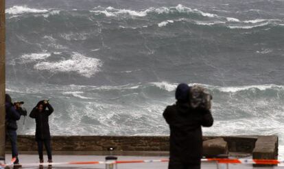 Varios periodistas graban las olas esta tarde en la costa de Muxía (A Coruña).