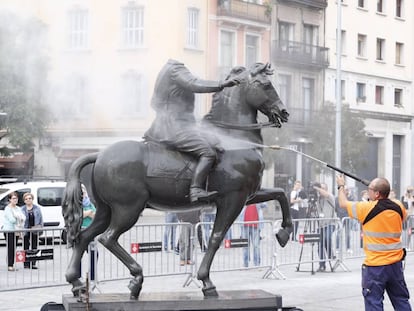 Uns operaris netegen l'estàtua de Franco decapitat, després que li hagin llançat ous.