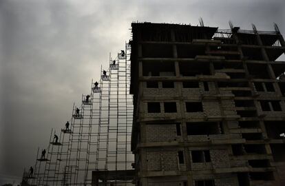 Trabajadores indios en un andamio desplazan varillas de acero desde el suelo hasta la parte superior de un edificio en construcción en Greater Noida (India). 

