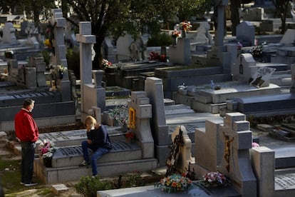 Una mujer llora sentada en una tumba, en el cementerio de La Almudena de Madrid.