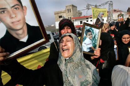 Una mujer muestra el retratro de su hijo, una de las 27 víctimas mortales, la mitad niños, que causó un ataque aéreo de Israel en la localidad de Qana, al sur de Líbano, donde se ha celebrado hoy un funeral.